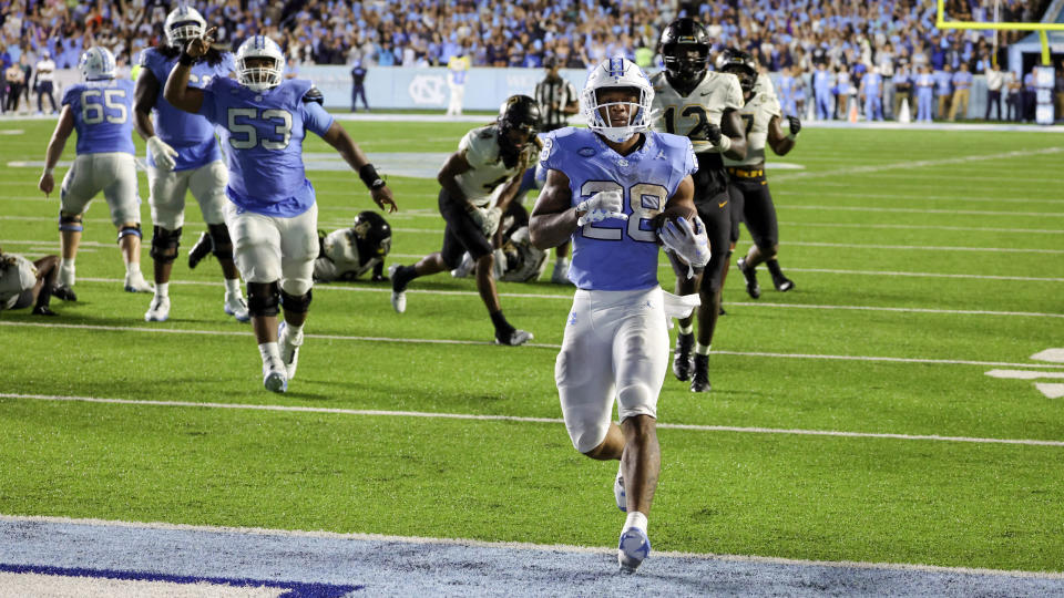 North Carolina running back Omarion Hampton (28) runs in for a touchdown with North Carolina offensive lineman Willie Lampkin (53) cheering him on during the second overtime of an NCAA college football game against Appalachian State, Saturday, Sept. 9, 2023, in Chapel Hill, N.C. (AP Photo/Reinhold Matay)