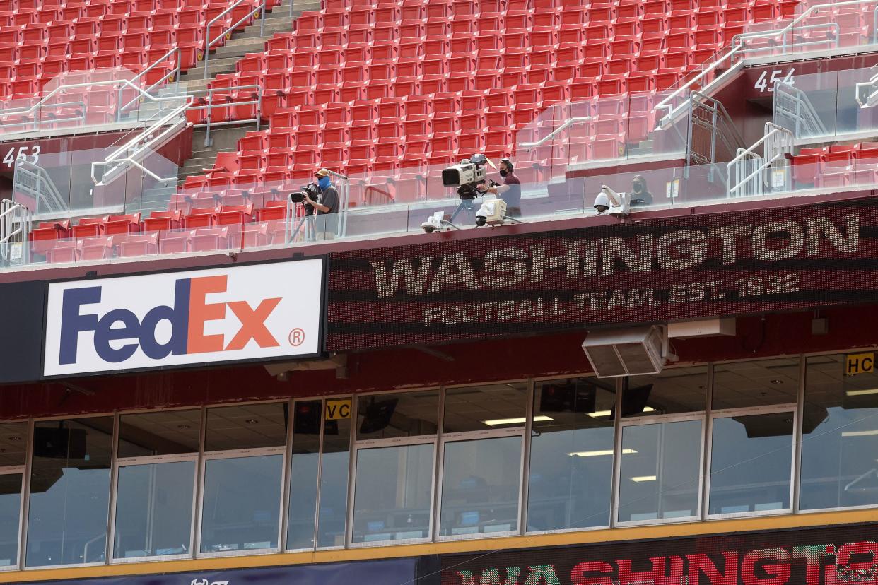 View of upper seating, empty, in the FedExField, Landover, Maryland, three camera people focused on the field, on a sunny day, 2020