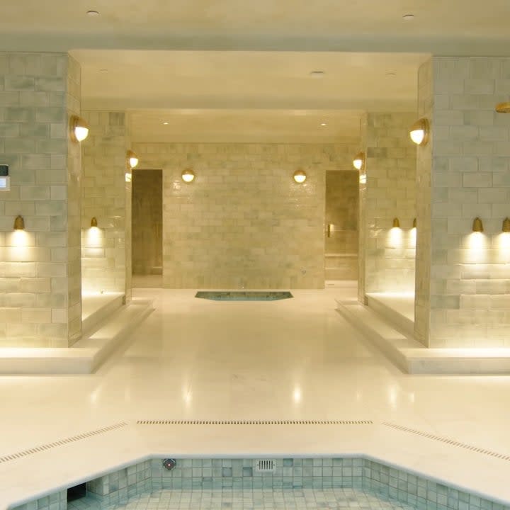 The house has a spa which has a rustic design to it with gold colored showers and faucets and dimmed lighting