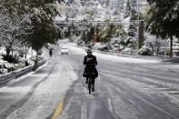 An ultra-Orthodox Jewish man rides his bicycle on a snow-covered road in winter in Jerusalem December 12, 2013. Schools and offices in Jerusalem and parts of the occupied West Bank were closed and public transport briefly suspended after heavy snowfall on Thursday. REUTERS/Amir Cohen (JERUSALEM - Tags: ENVIRONMENT)