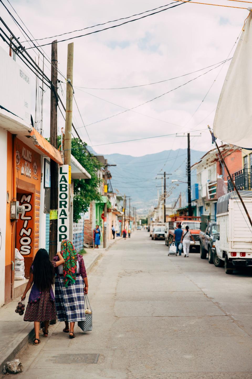 Woman and girl walk down the street with produce and freshly baked bread in tow after visiting the Sunday market in Tlacolula. The energy within the market was buzzing and electric, but as I made my way away from the center, the atmosphere quickly returned to that of the quiet village that surrounded it.