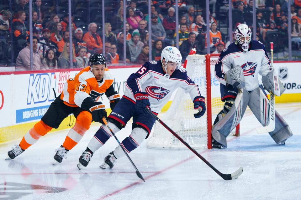 Columbus Blue Jackets' Tim Berni, center, skates the puck away with Philadelphia Flyers' Kevin Hayes, left, giving chase during the second period an NHL hockey game Tuesday, April 11, 2023, in Philadelphia. (AP Photo/Chris Szagola)