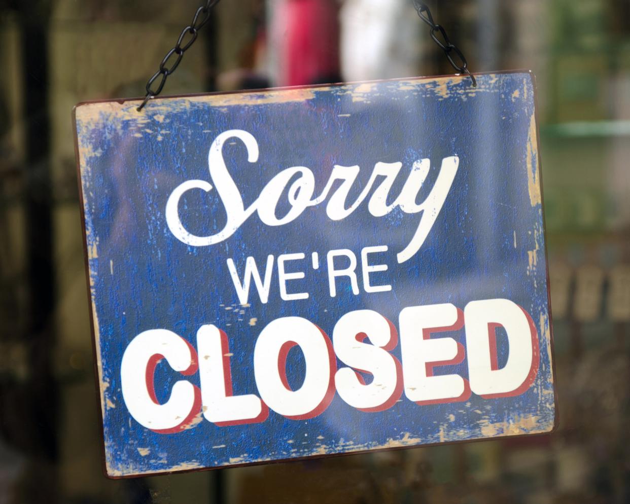 old blue 'Sorry, WE'RE CLOSED' sign hanging in a shop window