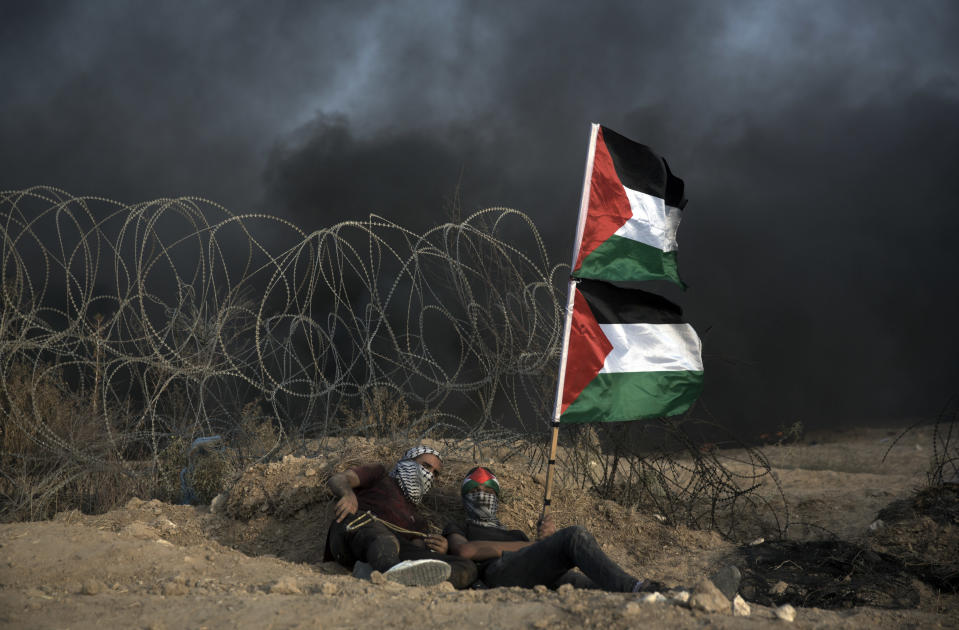 Palestinian protesters take cover at the Gaza Strip's border with Israel, Friday, Oct. 19, 2018. (AP Photo/Khalil Hamra)