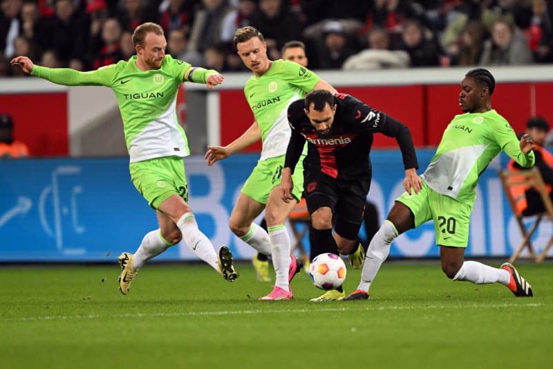 Leverkusen's Borja Iglesias (C) and Wolfsburg's Ridle Baku (R) battle for the ball during the German Bundesliga soccer match between Bayer Leverkusen and VfL Wolfsburg at BayArena. Federico Gambarini/dpa