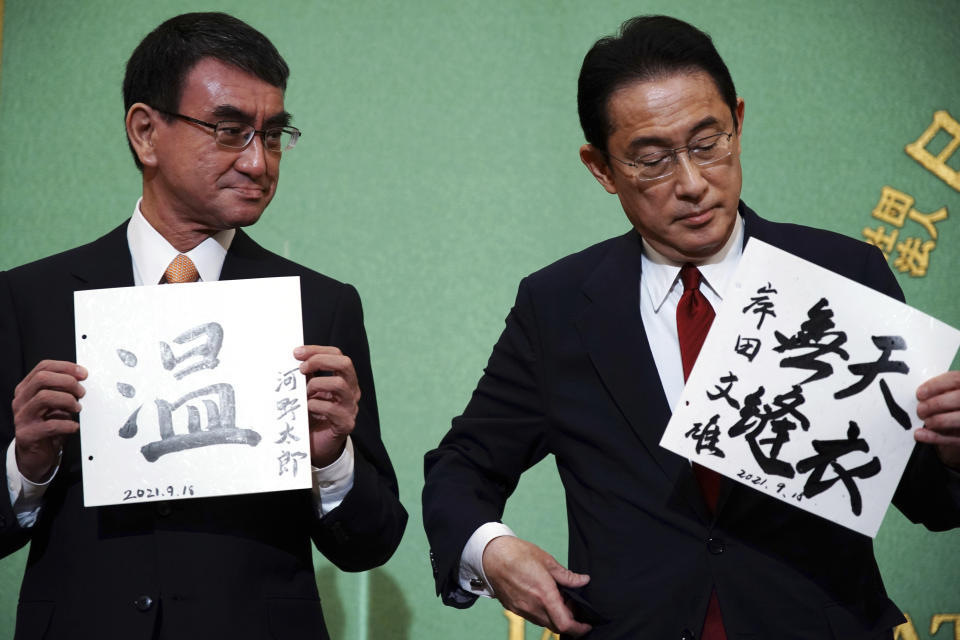 Taro Kono, left, the cabinet minister in charge of vaccinations, and Fumio Kishida, right, former foreign minister, two of the four candidates for the presidential election of the ruling Liberal Democratic Party pose with paper with their sign and words prior to a debate session hosted by the Japan National Press Club Saturday, Sept. 18, 2021 in Tokyo. The contenders not seen are Sanae Takaichi, former internal affairs minister, and Seiko Noda, former internal affairs minister. (AP Photo/Eugene Hoshiko, Pool)