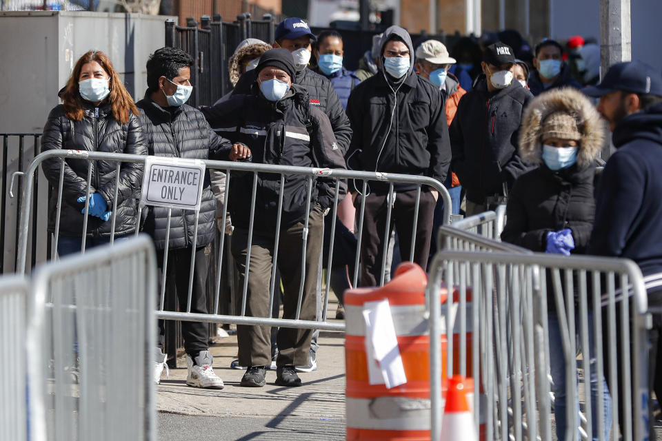 Patients wearing face masks and personal protective equipment wait on line for COVID-19 testing outside Elmhurst Hospital Center, Friday, March 27, 2020, in New York. The new coronavirus causes mild or moderate symptoms for most people, but for some, especially older adults and people with existing health problems, it can cause more severe illness or death. (AP Photo/John Minchillo)