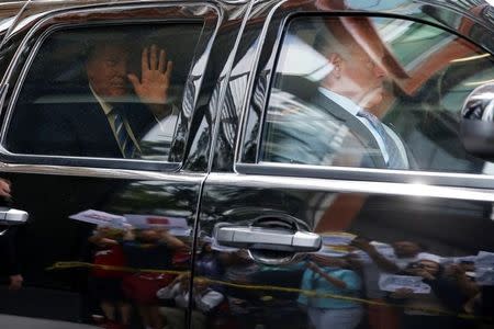 Demonstrators protesting Republican U.S. presidential candidate Donald Trump (in window, L) are reflected in the side of his car as he departs after he was deposed for a lawsuit involving partners in a restaurant venture at offices in Washington, U.S. June 16, 2016. REUTERS/Jonathan Ernst
