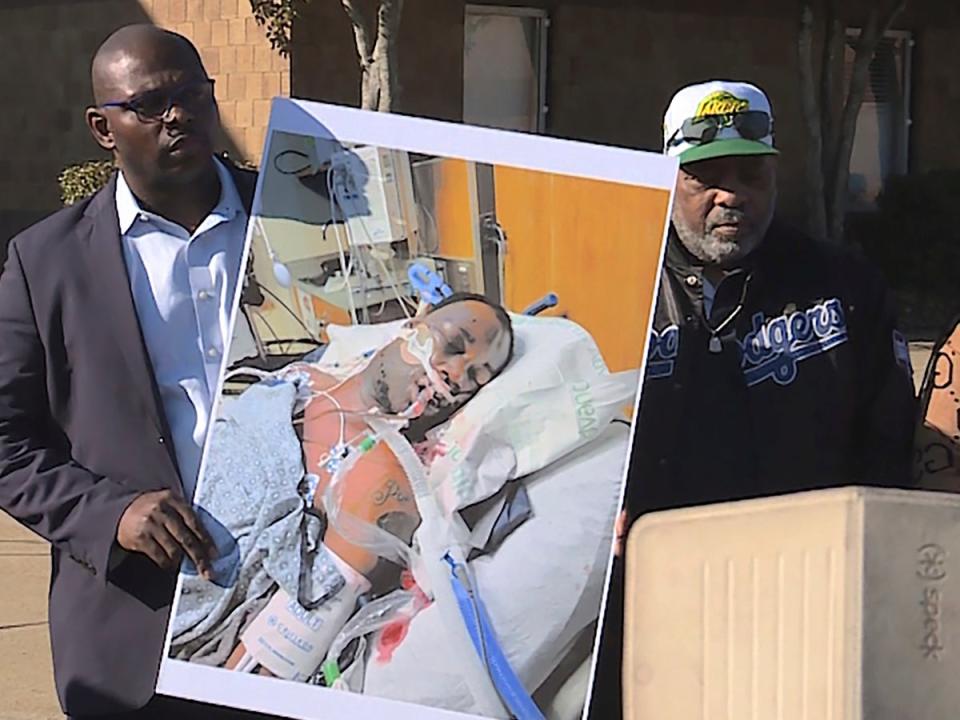 In this photo provided by WREG, Tyre Nichols' stepfather Rodney Wells, center, stands next to a photo of Nichols in the hospital after his arrest, during a protest in Memphis, Tenn., Saturday, Jan. 14, 2023 (AP)
