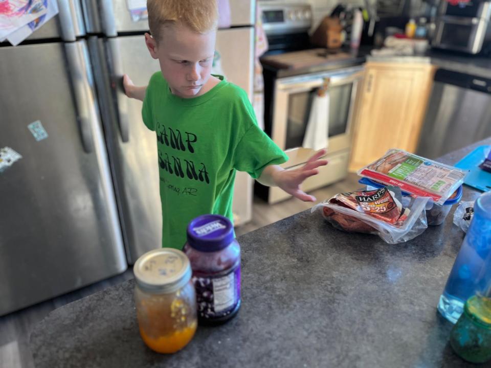 lisa's son taking deli meat and sandwich supplies out of a fridge and placing them on a kitchen counter