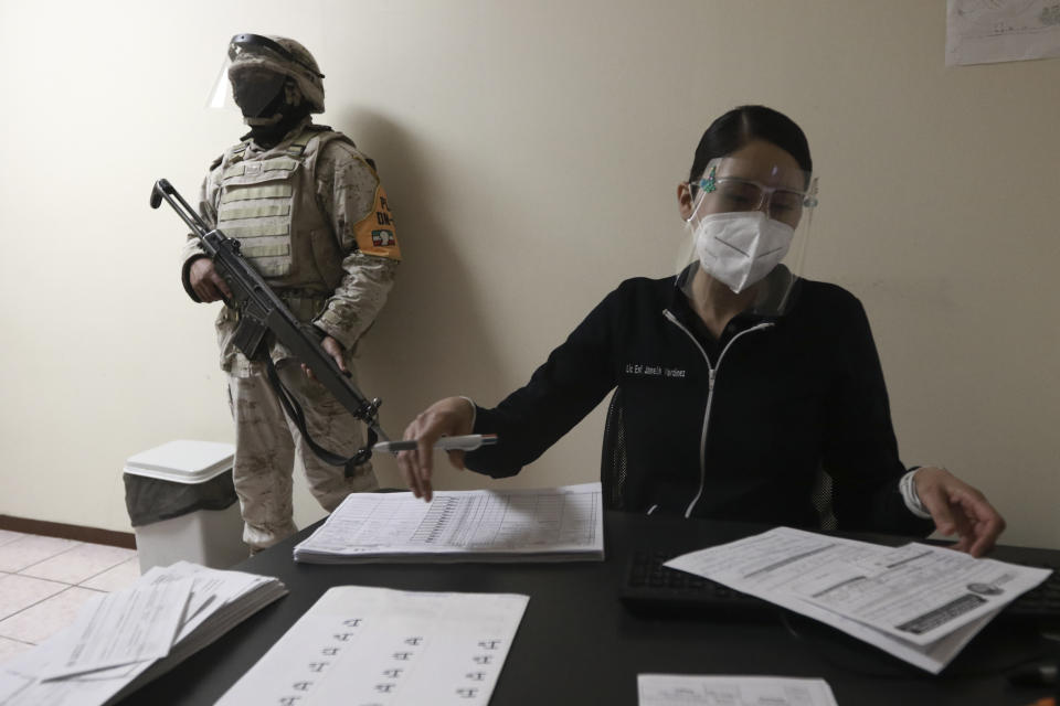 A soldier stands guard as healthcare workers are registered to receive shots of the Pfizer COVID-19 vaccine, on the first day of coronavirus vaccinations in Ciudad Juarez, Mexico, Wednesday, Jan. 13, 2021. (AP Photo/Christian Chavez)