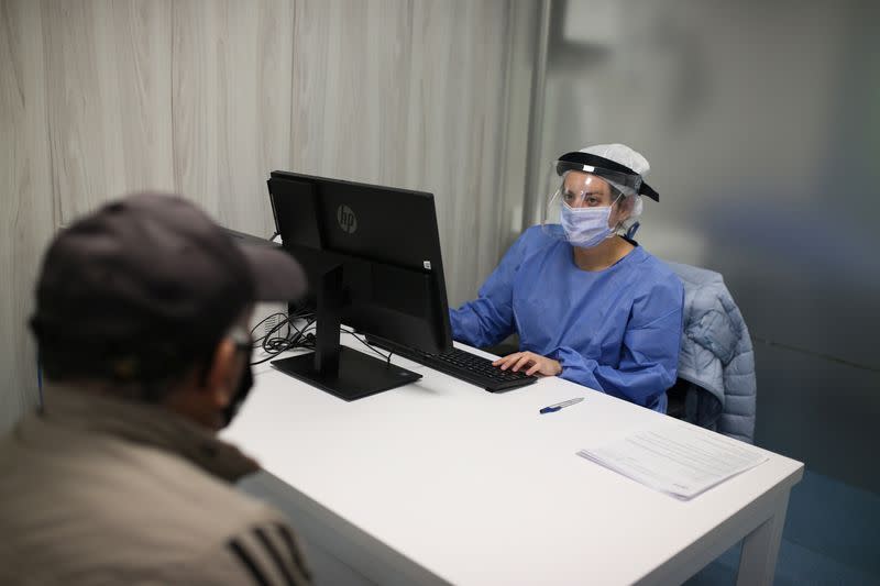 A doctor wearing protective gear talks to a patient inside a Zerenia clinic medical office, the first clinic specializing in medical marijuana treatments, in Bogota