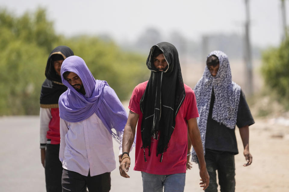 People cover their heads with scarves as protection against the harsh sun on a hot summer day in Jammu, India, Tuesday, May.28, 2024. (AP Photo/Channi Anand)