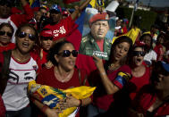 One woman holds a picture of Venezuela's late president Hugo Chavez with a message that reads in Spanish; "Eternal Commander" while another woman holds a representation of Venezuela's national flag during an event marking the first anniversary of Chavez's death in Havana, Cuba, Wednesday, March 5, 2014. (AP Photo/Ramon Espinosa)