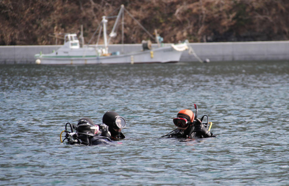 In this Sunday, March 9, 2014 photo, Yasuo Takamatsu, right, floats in the sea with his instructor, second from right, during a diving lesson at Takenoura bay, Miyagi prefecture, northern Japan. Nearly three years after the earthquake and tsunami disaster that struck Japan's northern pacific coastline, Takamatsu is learning to scuba dive in hopes of finding his wife. As Japan marks the third anniversary of the 2011 tsunami Tuesday, 2,636 people remain missing, their bodies presumably swept out to sea. Another 15,884 have been confirmed dead. (AP Photo/Koji Ueda)