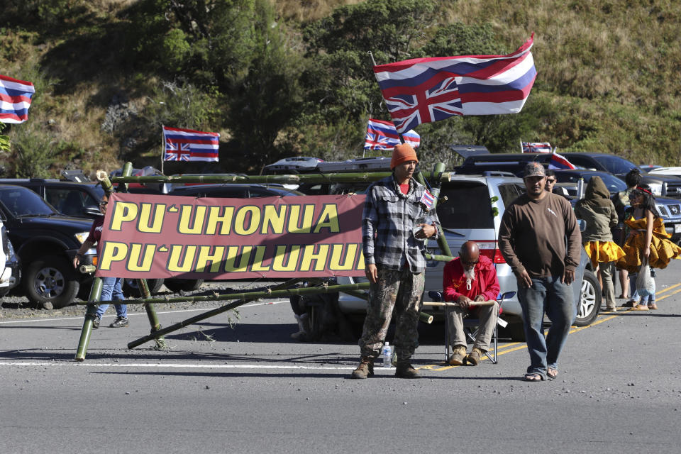 Native Hawaiian activists gather at the base of Hawaii's Mauna Kea, Sunday, July 14, 2019. Hundreds of demonstrators are gathered at the base of Hawaii's tallest mountain to protest the construction of a giant telescope on land that some Native Hawaiians consider sacred. State and local officials will try to close the road to the summit of Mauna Kea Monday morning to allow trucks carrying construction equipment to make their way to the top. Officials say anyone breaking the law will be prosecuted. Protestors have blocked the roadway during previous attempts to begin construction and have been arrested. (AP Photo/Caleb Jones)