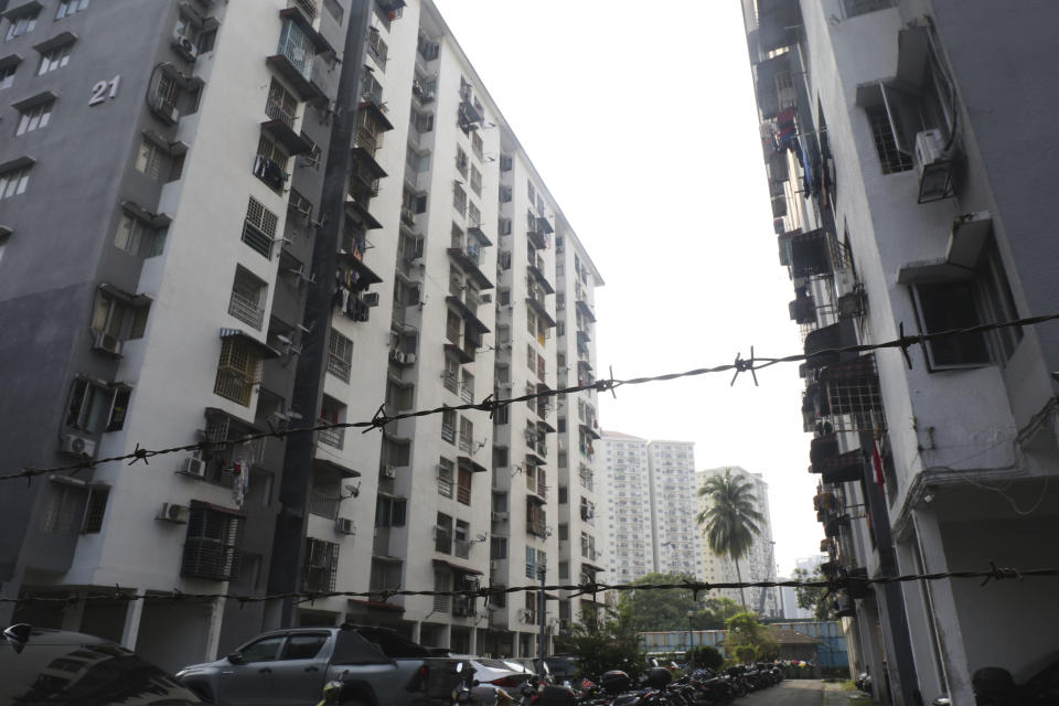 A barbed wire fence surrounds an apartment building in a Kuala Lumpur, Malaysia, neighborhood where Rohingya child brides live, on Oct. 9, 2023. (AP Photo/Victoria Milko)