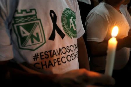 A fan of the Atletico Nacional soccer club holds a candle and wears a shirt in support while paying tribute to the players of Brazilian club Chapecoense killed in the recent airplane crash, in Medellin, Colombia, November 30, 2016. REUTERS/Fredy Builes