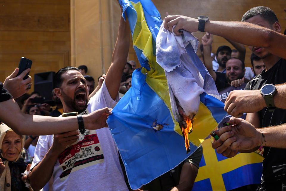 FILE - Scores of angry protesters burn representations of the Swedish and Israeli flags during a rally to denounce burning of Islam's holy book 'Quran', after Friday prayers outside Mohammad al-Amin Mosque in downtown Beirut, Lebanon, Friday, July 7, 2023. The targeting of Swedish citizens in an attack in Brussels on the night of Monday, Oct. 16, 2023 has shocked the Scandinavian country, yet the government had been warning for months that Swedes were at greater risk since a recent string of public desecrations of the Quran, Islam's holy book, by a handful of anti-Islam activists. (AP Photo/Hassan Ammar, File)