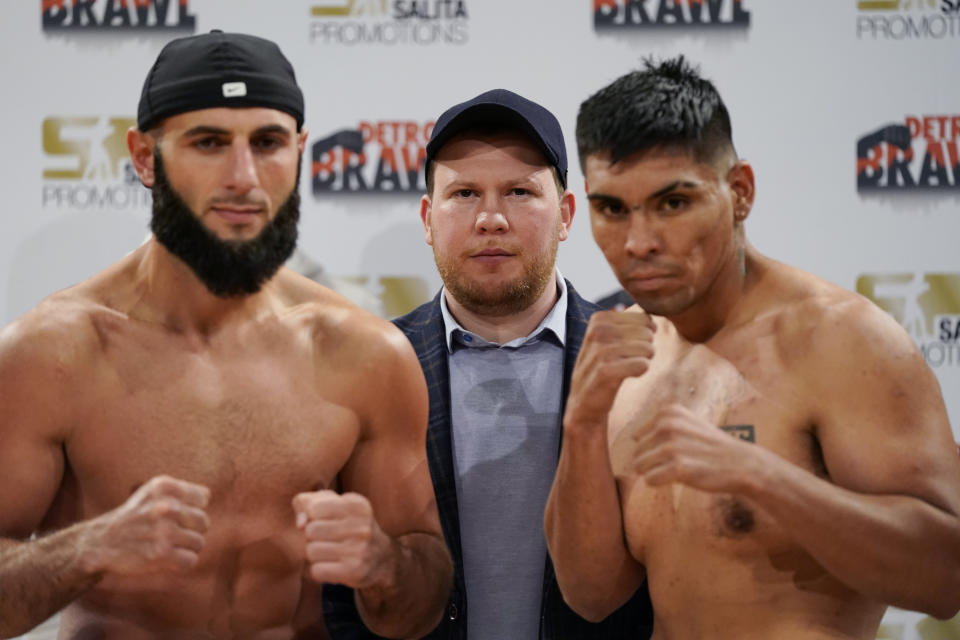 Boxing promoter Dmitry Salita, center, watches as Ali Izmailov of Miami, left, and Abraham Tebes of Iquique Chile, stand after their weigh-in, Friday, April 1, 2022, in Dearborn, Mich. Promoters Carlos Llinas and Salita are pushing the sport in the Detroit area with a periodic series of bouts in smaller venues in hopes of bringing it back to the masses. Llinas and Salita each are aiming to promote several boxing cards this year. (AP Photo/Carlos Osorio)