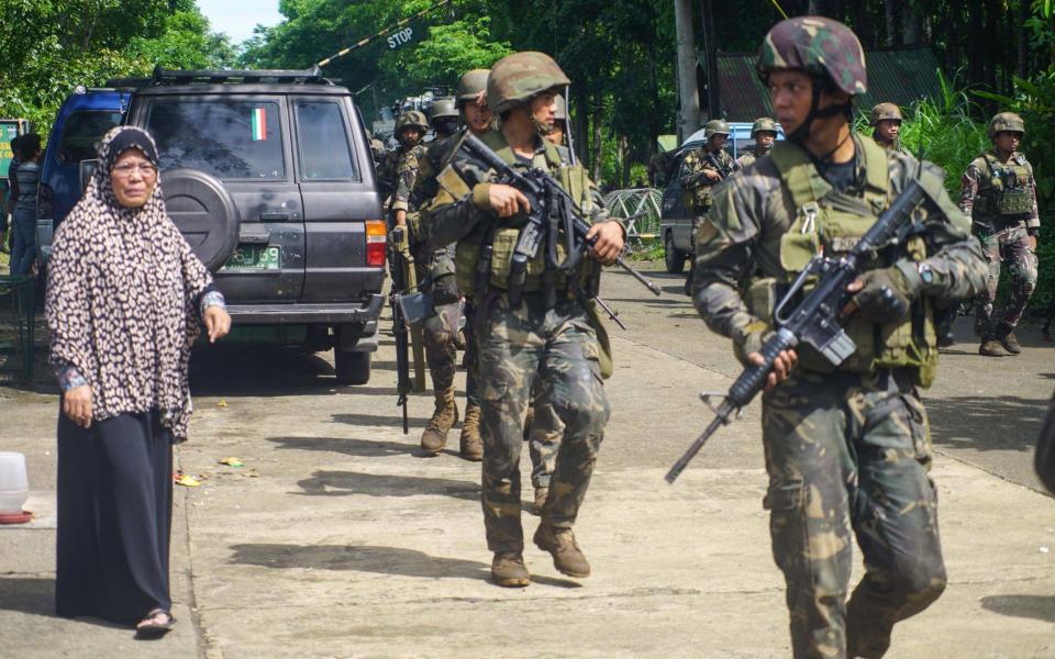 Filipino fleeing villagers view patroling soldiers following reports of alleged fresh clashes between government troops and rebels in Marawi City - Credit: EPA