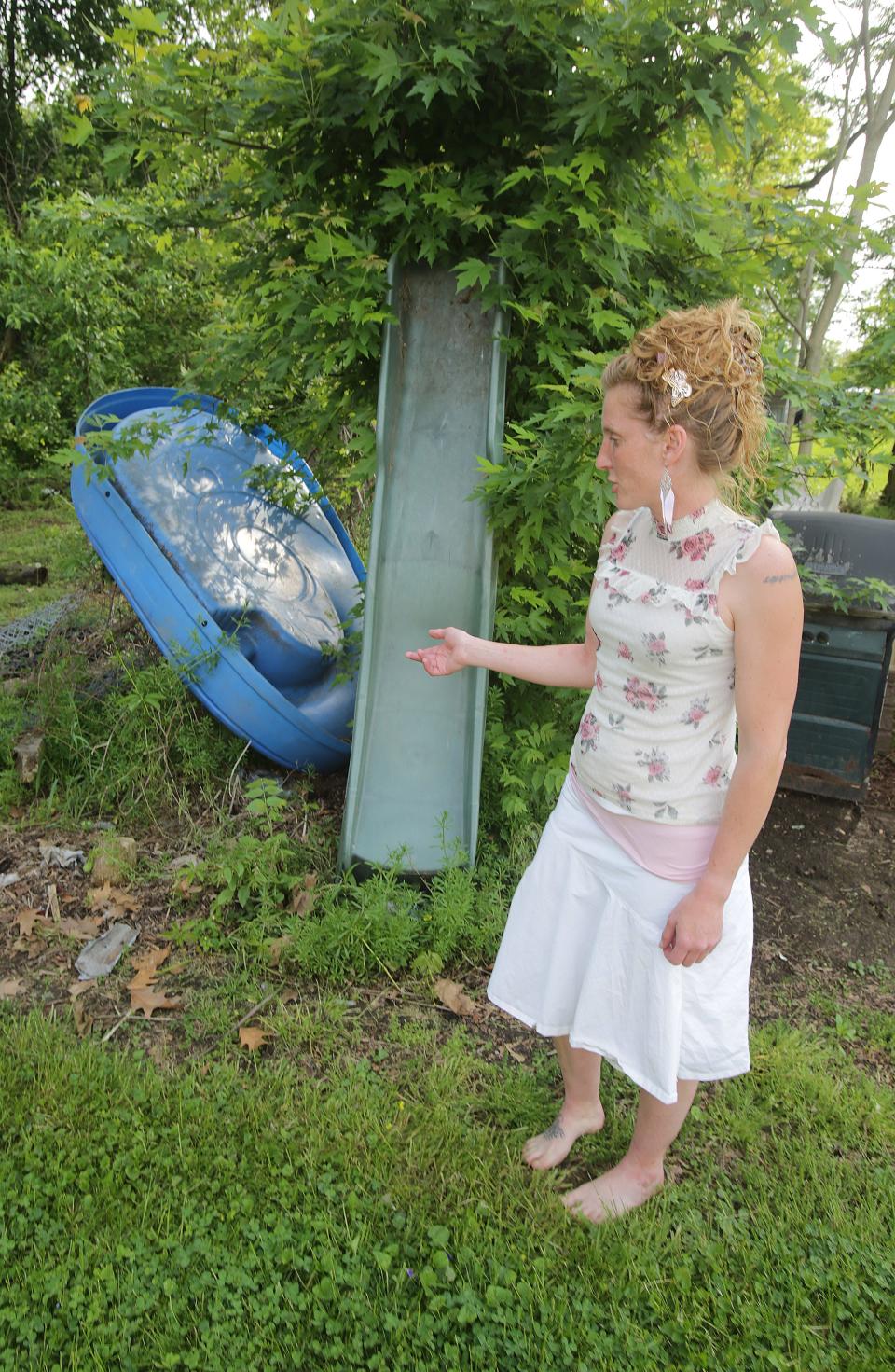 Amanda Martin shows some of the junk left on property next to her southwest Massillon home. The junk will be cleaned up by IMPACT Massillon in June.