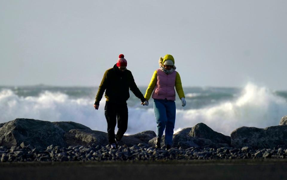 People walk along the seafront in Doolin in County Clare on the west coast of Ireland