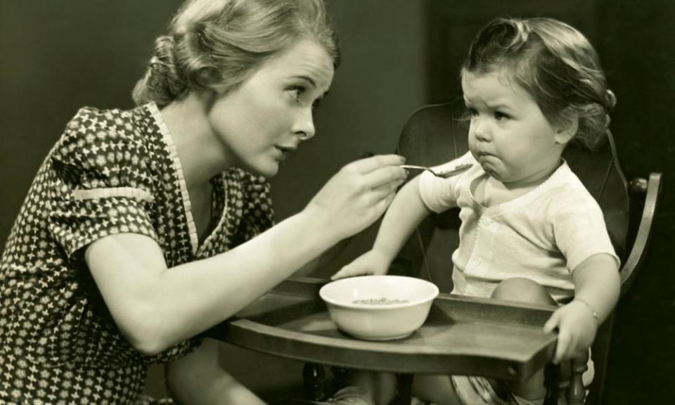 Monochrome photograph of woman trying to feed baby