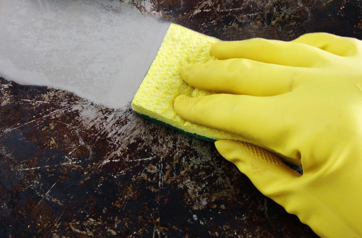 cleaning a greasy pan with yellow latex gloves