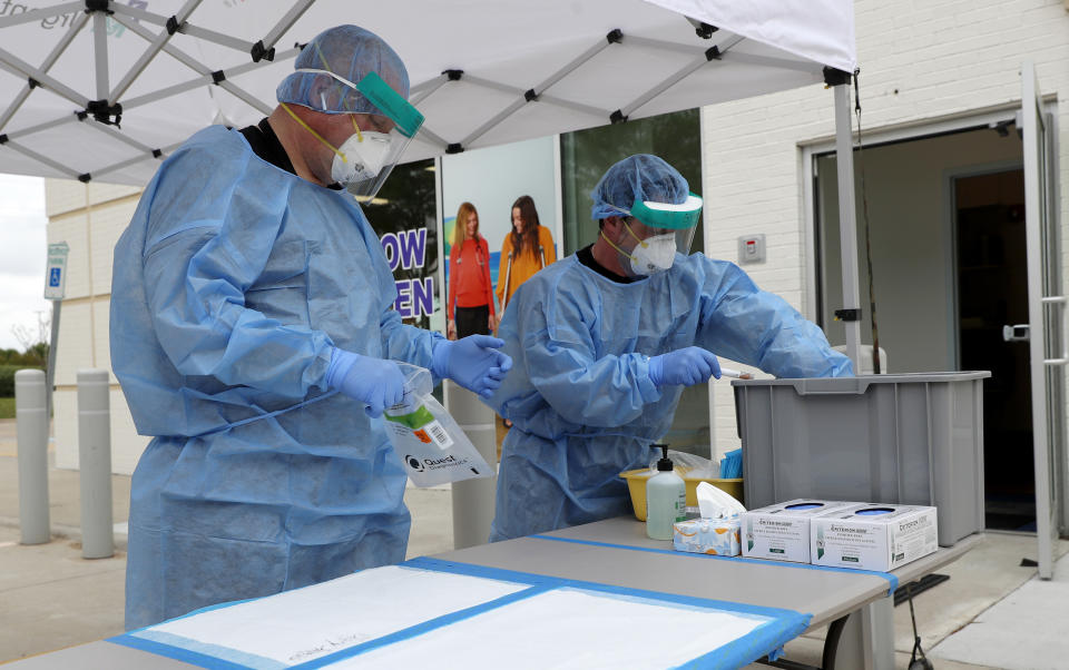 FILE - In this April 2, 2020, file photo, registered nurses Jonathan Fisk, left, and Patrick LaFontaine set up a COVID-19 testing station for pre-screened pediatric patients outside a Children's Health PM Urgent Care facility in Richardson, Texas. A recent Pew Research Center survey found a steady diet of stressful news from the coronavirus pandemic is stressing many consumers out. The poll shows that while nearly 9 in 10 Americans are following pandemic news either very or fairly closely, most people say they need to take breaks. (AP Photo/Tony Gutierrez, File)