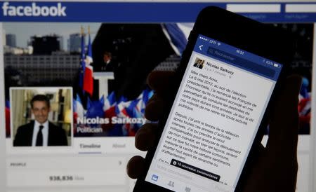 An illustration photo shows the message of former French President Nicolas Sarkozy on his Facebook page displayed on a mobile phone internet browser held in front of a computer screen which also displays his Facebook page in Paris September 19, 2014. REUTERS/Christian Hartmann