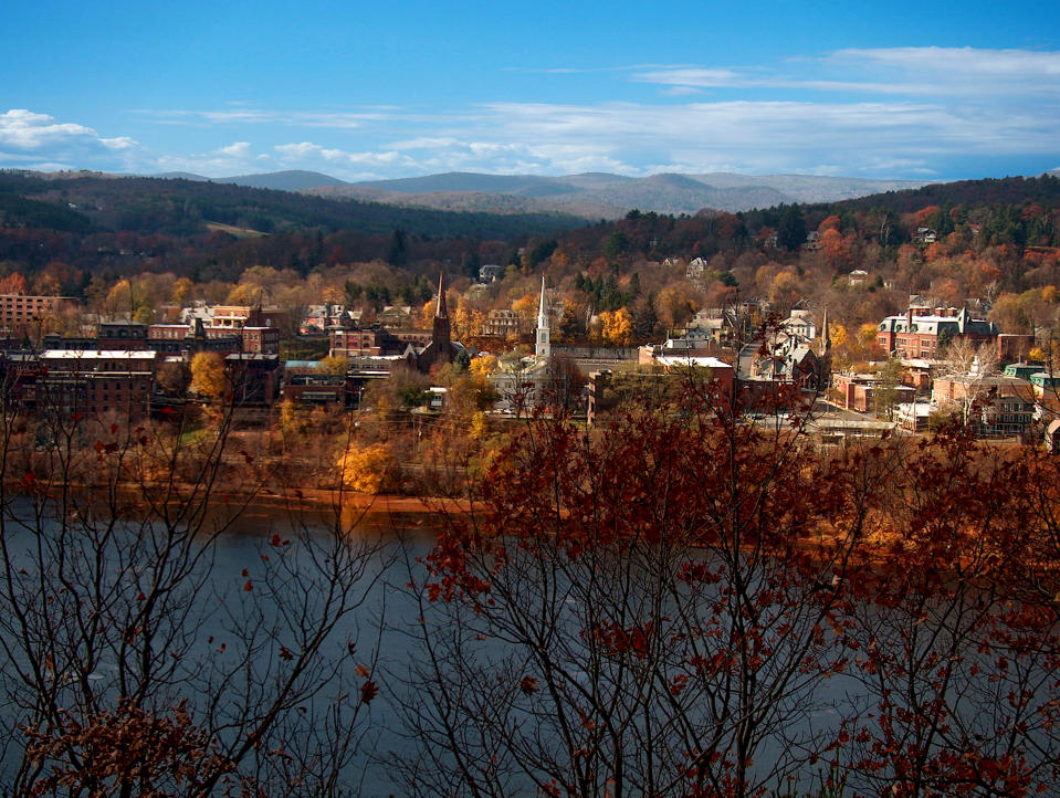 Scenic view of a town with buildings amid autumn trees and distant hills