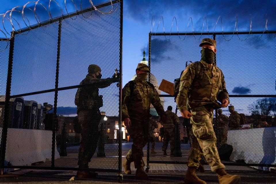Members of the National Guard walk through a security fence surrounding the U.S. Capitol