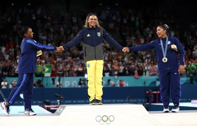 <p>Naomi Baker/Getty Images</p> Gold medalist Rebeca Andrade (C) of Team Brazil, silver medalist Simone Biles (L) of Team United States and bronze medalist Jordan Chiles (R) of Team United States