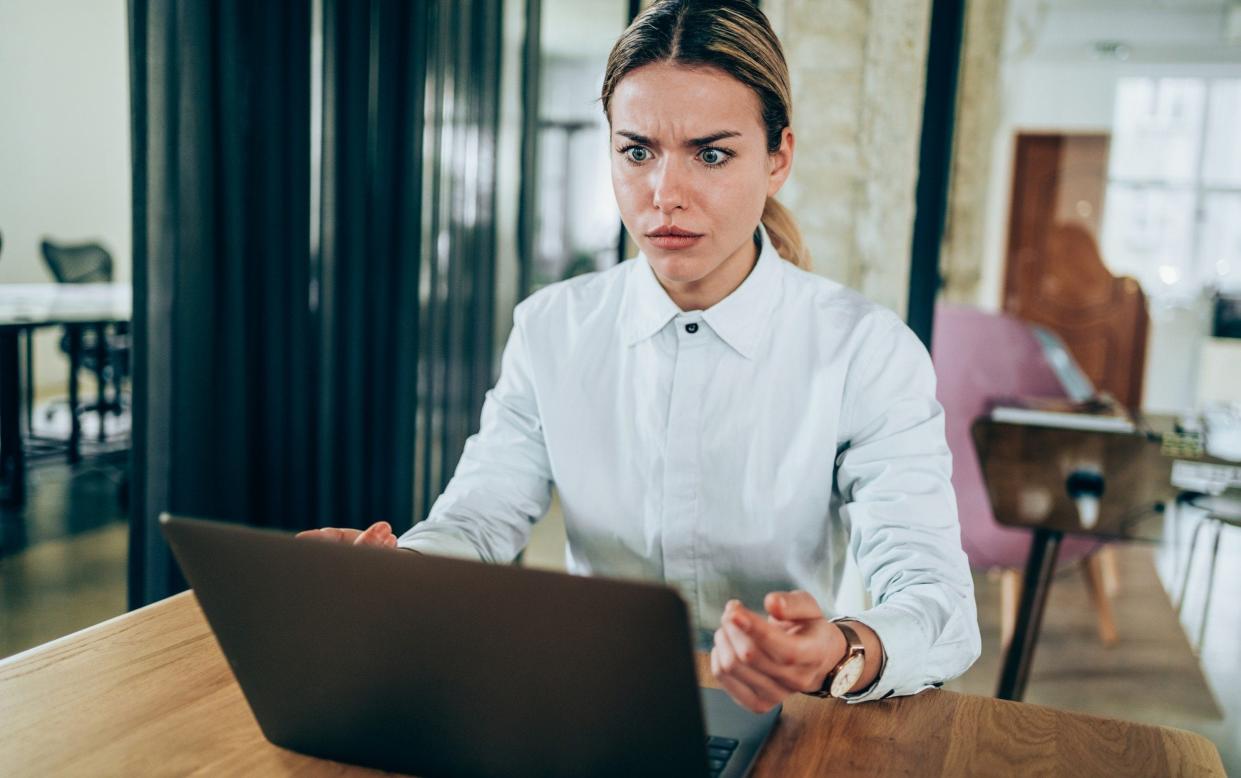 a woman looking angry at her laptop - E+