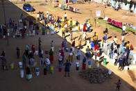 In this April, 24, 2020, photo, people wait to fetch water from a row of communal taps that the group Doctors Without Borders provided in a suburb of Harare, Zimbabwe. For people around the world who are affected by war and poverty, the simple act of washing hands is a luxury. In Zimbabwe, clean water is often saved for daily tasks like doing dishes and flushing toilets. (AP Photo/Tsvangirayi Mukwazhi)