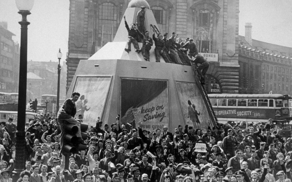 15th August 1945: A few minutes after the Japanese surrender was announced, Piccadilly Circus was filled with a jubilant crowd, some of whom climbed on the plinth of the Statue of Eros - Keystone/Getty Images