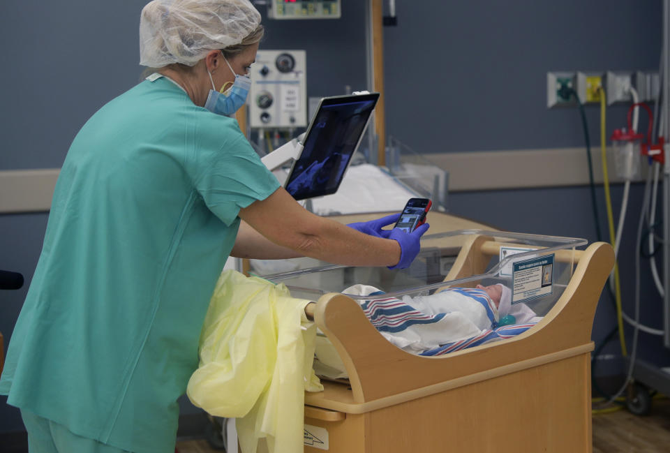 Nurse Amanda Vaughan takes photos and helps new mom Clarissa Munoz, who is infected with COVID-19, see her baby via iPad at DHR Health, Wednesday, July 29, 2020, in McAllen, Texas. Munoz was separated from her child after giving birth. (AP Photo/Eric Gay)