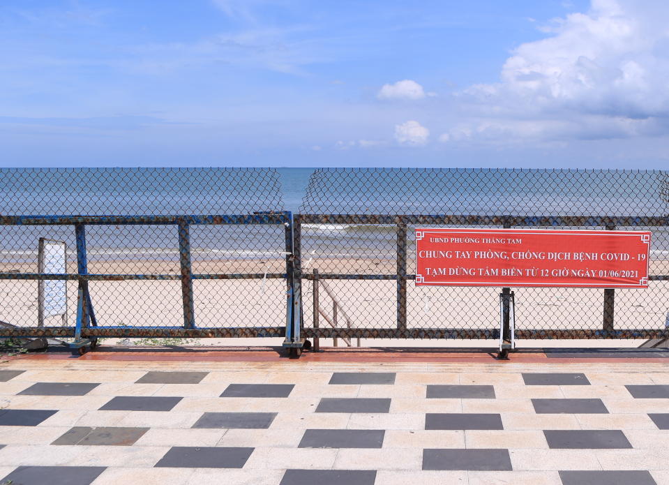 Entrance to a beach is barricaded with sign read in Vietnamese "Fight COVID-19 together, no beach activities" in Vung Tau, Vietnam, Monday, Sept. 20, 2021. In Vung Tau, just outside Ho Chi Minh city, streets are sealed and checkpoints are set up to control the movement of people. Barbed wire, door panels, steel sheets, chairs and tables are among materials being used to fence up alleys and isolate neighborhoods.(AP Photo/Hau Dinh)