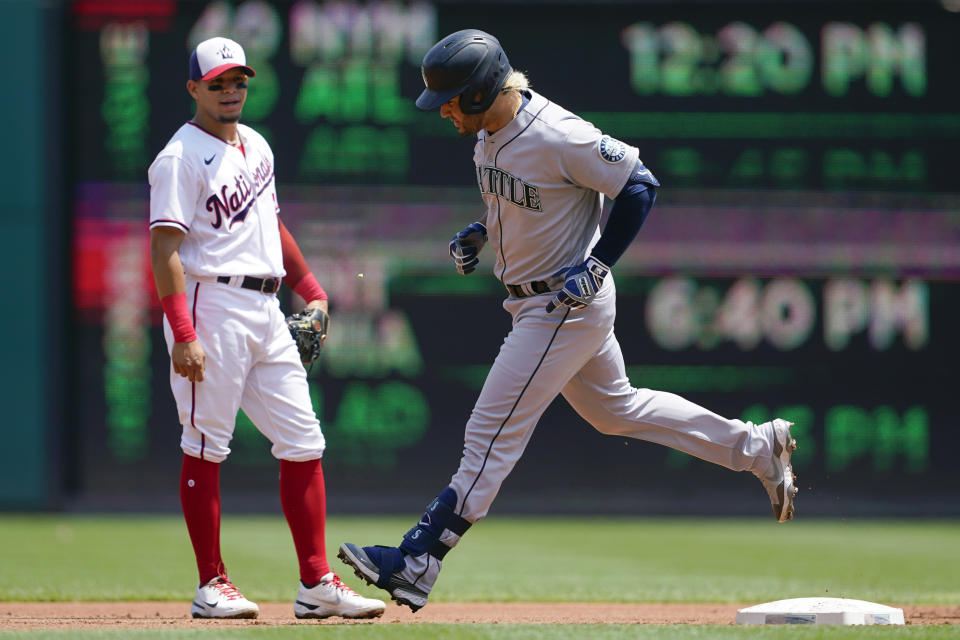 Seattle Mariners' Eugenio Suarez rounds the bases past Washington Nationals second baseman Cesar Hernandez after hitting a three-run home run in the first inning of the first game of a baseball doubleheader, Wednesday, July 13, 2022, in Washington. (AP Photo/Patrick Semansky)