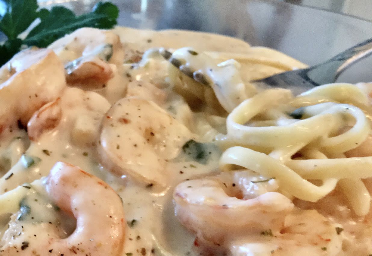 Close up of chicken and shrimp fettuccine alfredo being picked up with a fork