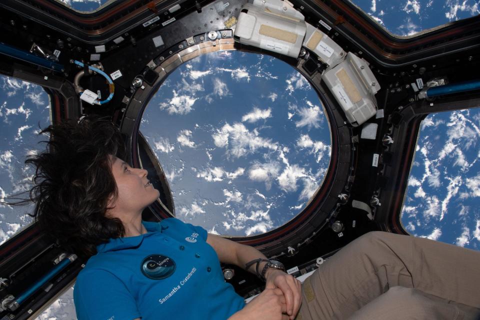 astronaut samantha cristoforetti looks through space station cupola window at ocean and clouds below