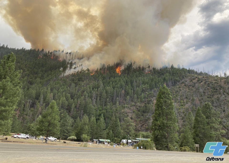 In this photo provided by Caltrans, smoke rises from the Head Fire in Klamath National Forest, Calif., on Tuesday Aug. 15, 2023. A wildfire pushed by gusty winds from a thunderstorm raced through national forest land near California's border with Oregon, prompting evacuations in the rural area. The blaze in Siskiyou County was one of at least 19 fires that erupted in the Klamath National Forest as thunderstorms rolling through the area brought lightning and downdrafts that drove the flames through timber and rural lands. (Roger Matthews/Catrans via AP)