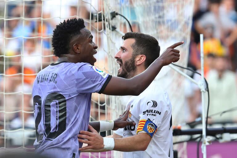 ARCHIVO - Vinicius Junior, izquierda, del Real Madrid, discute con los aficionados del Valencia luego de que éstos lo insultaran por su color de piel durante un partido entre ambos equipos el domingo 21 de mayo de 2023, en Valencia, España. José Luis Gaya del Valencia intenta contener al futbolista brasileño. (AP Foto/Alberto Saiz, archivo)