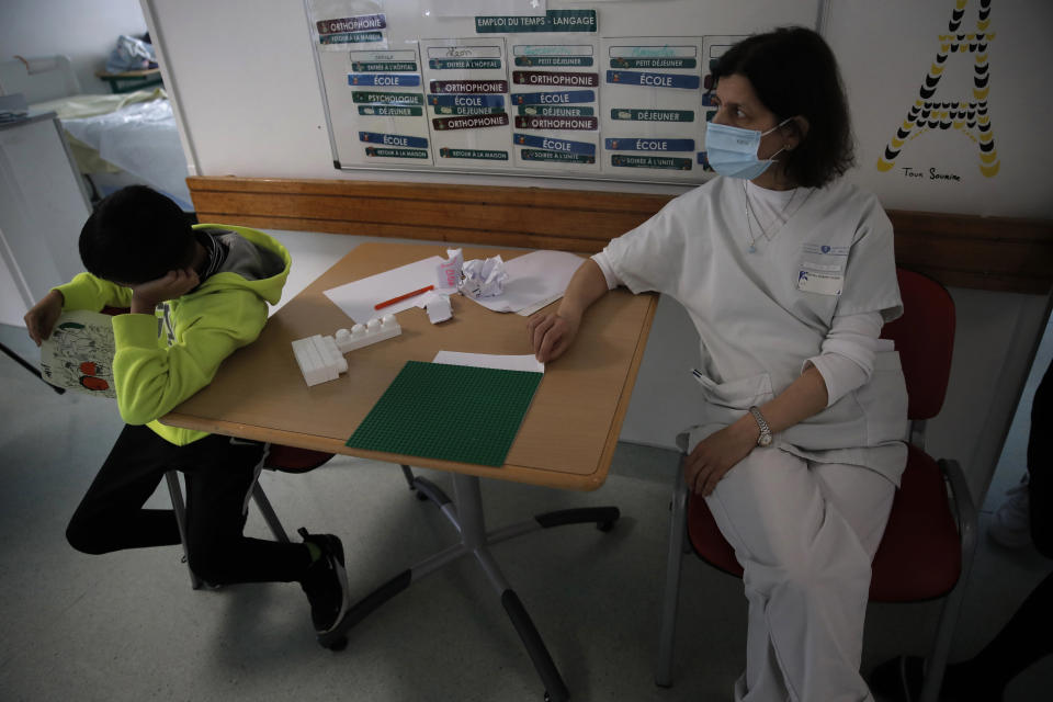 A young boy sits with a member of the medical staff in the pediatric unit of the Robert Debre hospital, in Paris, France, Tuesday, March 2, 2021. France's busiest pediatric hospital has seen a doubling in the number of children and young teenagers requiring treatment after attempted suicides. Doctors elsewhere report similar surges, with children — some as young as 8 — deliberately running into traffic, overdosing on pills and otherwise self-harming. (AP Photo/Christophe Ena)