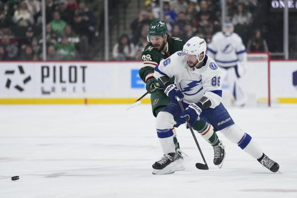 Tampa Bay Lightning right wing Nikita Kucherov, right, and Minnesota Wild center Frederick Gaudreau vie for the puck during the first period of an NHL hockey game Thursday, Jan. 4, 2024, in St. Paul, Minn. (AP Photo/Abbie Parr)