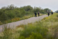 U.S. Border Patrol agents and an Arizona Fish and Game Officer search for a group of migrants evading capture along a road at the base of the Baboquivari Mountains, Thursday, Sept. 8, 2022, near Sasabe, Ariz. The desert region located in the Tucson sector just north of Mexico is one of the deadliest stretches along the international border with rugged desert mountains, uneven topography, washes and triple-digit temperatures in the summer months. Border Patrol agents performed 3,000 rescues in the sector in the past 12 months. (AP Photo/Matt York)
