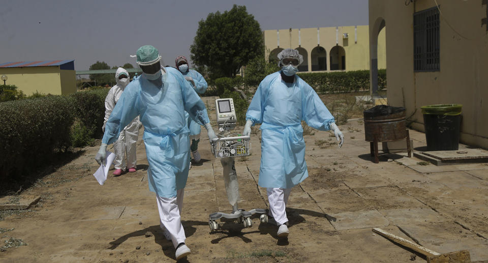 Medical works moving medical equipment while wearing PPE in Chad.