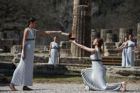 Greek actress Xanthi Georgiou, left, playing the role of the High Priestess, holds the torch during the flame lighting ceremony at the closed Ancient Olympia site, birthplace of the ancient Olympics in southern Greece, Thursday, March 12, 2020. Greek Olympic officials are holding a pared-down flame-lighting ceremony for the Tokyo Games due to concerns over the spread of the coronavirus. Both Wednesday's dress rehearsal and Thursday's lighting ceremony are closed to the public, while organizers have slashed the number of officials from the International Olympic Committee and the Tokyo Organizing Committee, as well as journalists at the flame-lighting. (AP Photo/Thanassis Stavrakis)