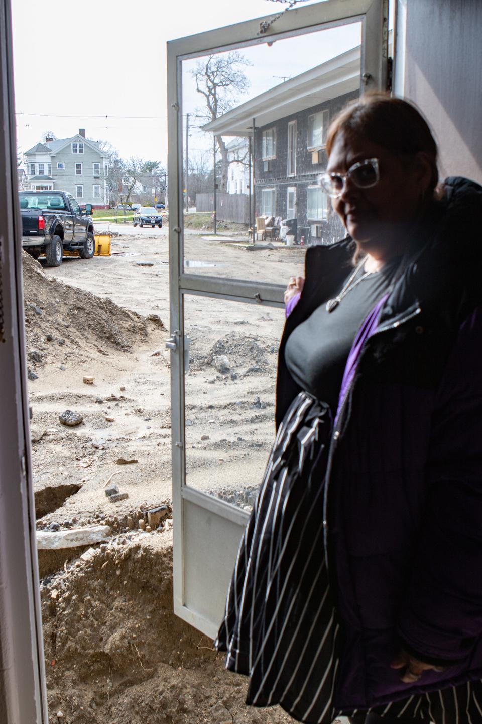 Melissa Potter holds open the front door of her apartment to reveal a 6-foot trench at 1890 Broad St. in Cranston.